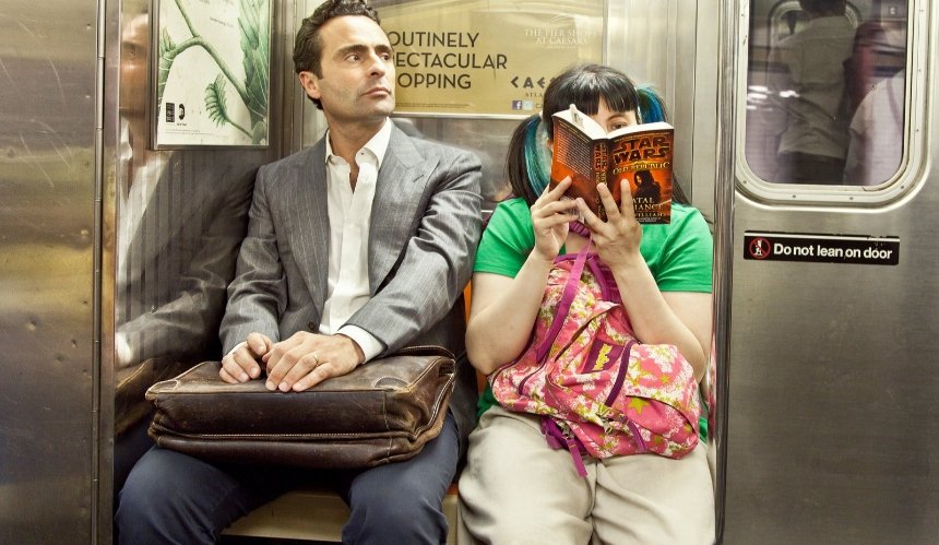 Дівчина, яка читає книжку у метро