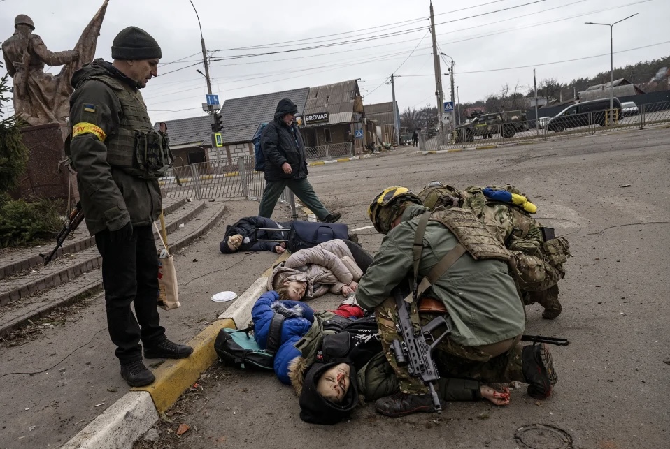 Українські військові оглядають родину, яку вбили росіяни під час евакуації з Ірпіня, 6 березня.